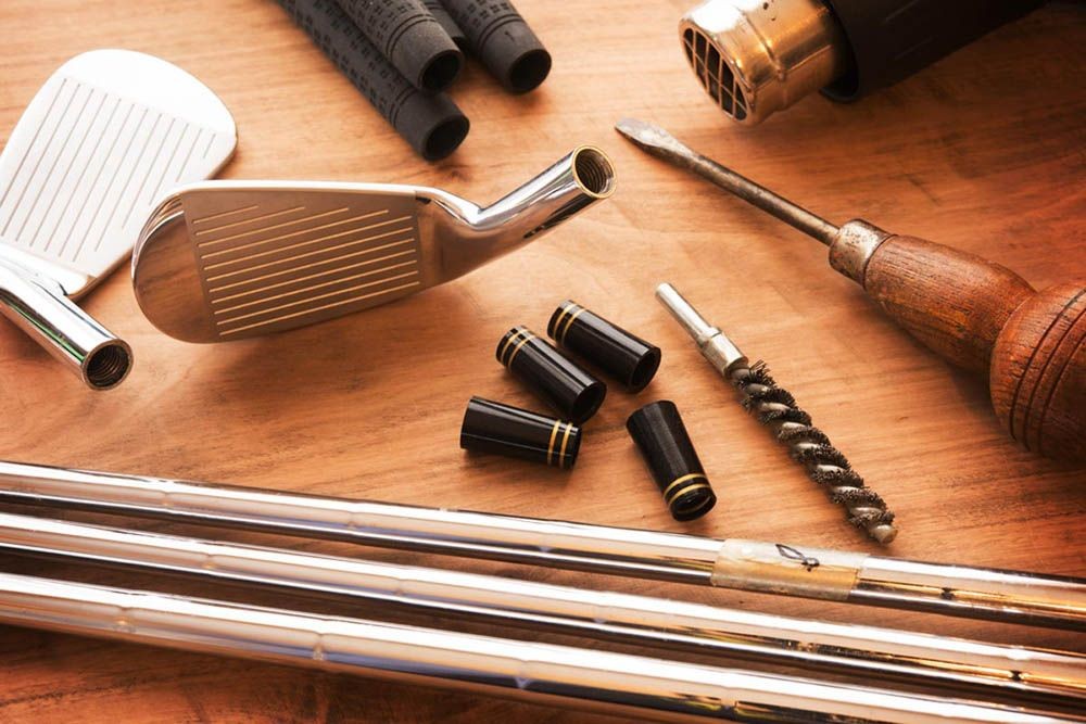 Golf club components, grips, and tools arranged on a wooden surface.